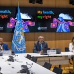 The hands of a health care worker wearing gloves hold a vial and a swab that